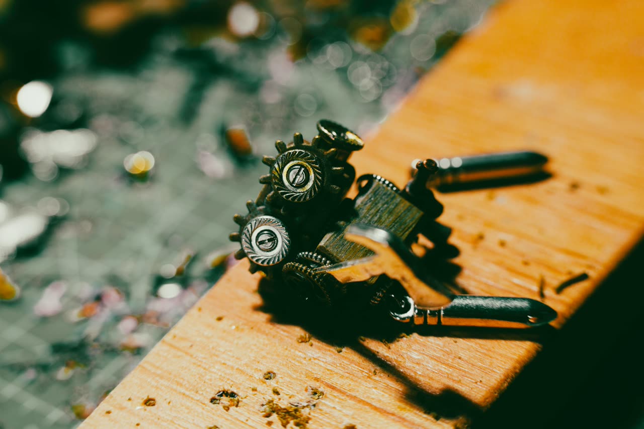 Small gears, a spanner and metal parts lying loose on a scuffed wooden bench